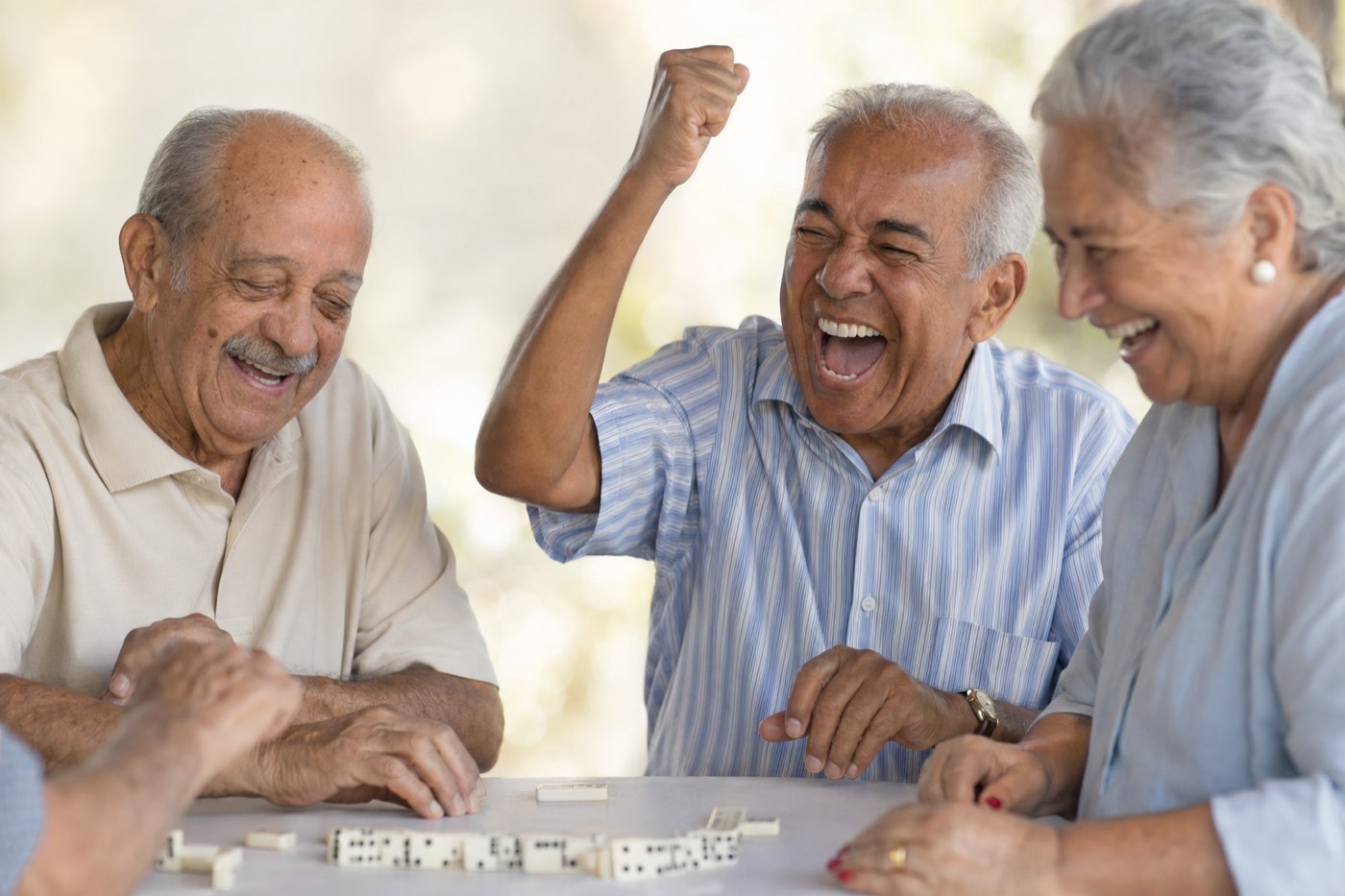 Idosos rindo juntos jogando dominó